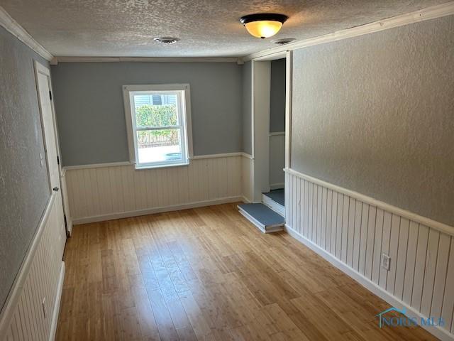 203 S Main, Hicksville, OH 43526 - empty room featuring wood-type flooring, ornamental molding, wainscoting, and a textured ceiling