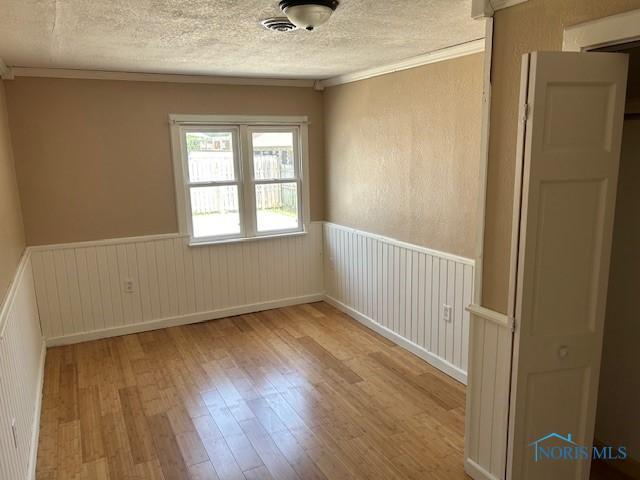 203 S Main, Hicksville, OH 43526 - unfurnished room with hardwood / wood-style floors, a wainscoted wall, a textured ceiling, and ornamental molding
