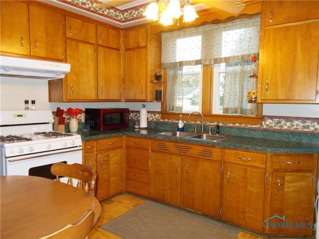 431 Fillmore St, Napoleon, OH 43545 - kitchen featuring white gas stove, under cabinet range hood, a ceiling fan, and brown cabinets