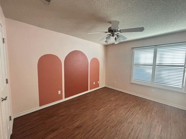 spare room with a textured ceiling, dark wood-type flooring, and ceiling fan