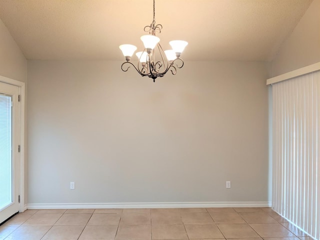 tiled spare room featuring an inviting chandelier, a wealth of natural light, and a textured ceiling