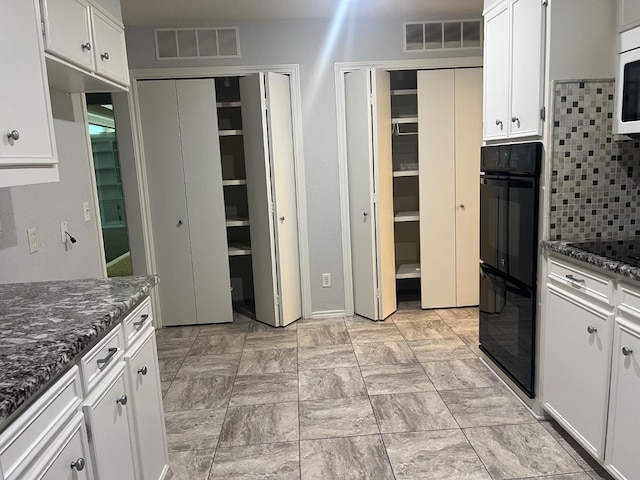 kitchen featuring white cabinetry, dark stone counters, tasteful backsplash, and black appliances