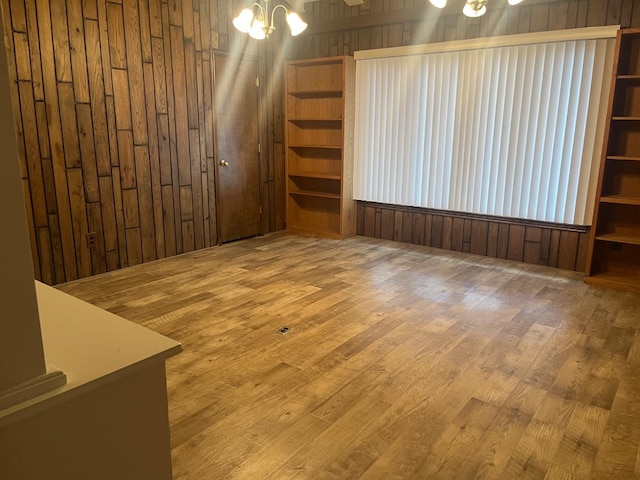 interior space featuring hardwood / wood-style floors, wooden walls, and a chandelier