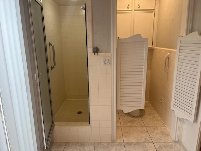 bathroom featuring tile patterned flooring, a shower with door, and tile walls