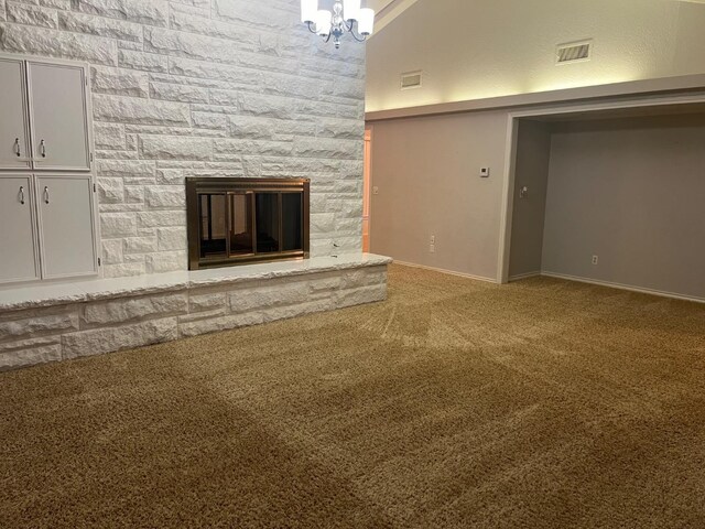 unfurnished living room with a stone fireplace, a chandelier, and carpet