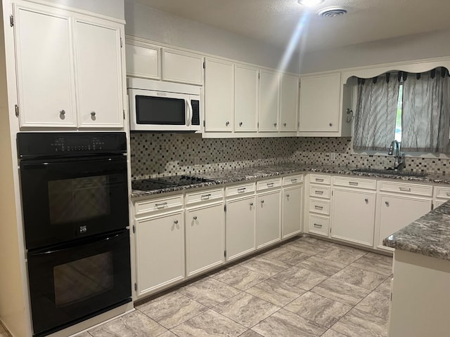 kitchen with sink, decorative backsplash, dark stone counters, and black appliances