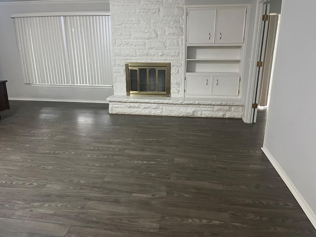 unfurnished living room featuring dark hardwood / wood-style floors and a stone fireplace