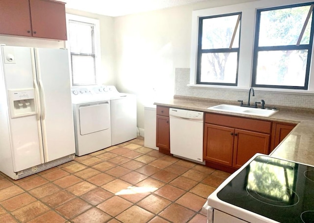 kitchen featuring white appliances, separate washer and dryer, sink, and backsplash