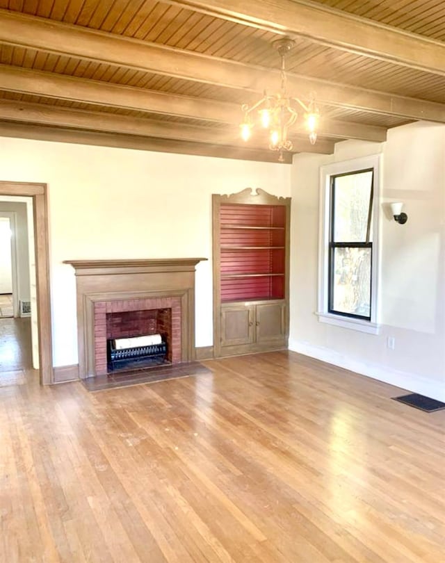 unfurnished living room featuring an inviting chandelier, a fireplace, wood ceiling, and wood-type flooring