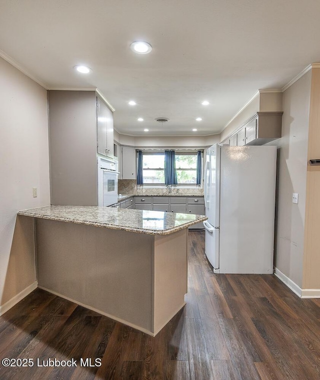 3423 60th St, Lubbock, TX 79413 - kitchen with white appliances, a peninsula, light stone countertops, dark wood finished floors, and ornamental molding