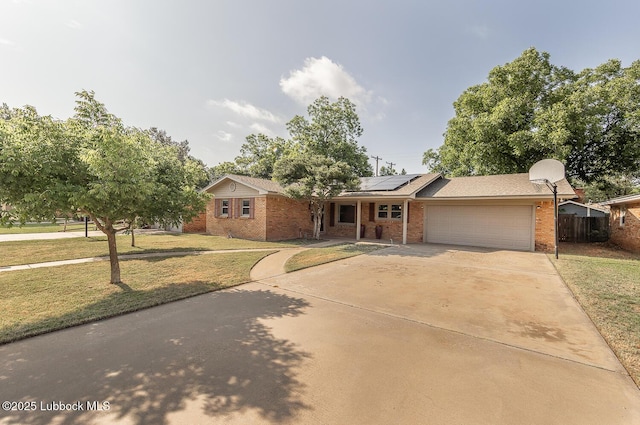 3423 60th St, Lubbock, TX 79413 - ranch-style house featuring brick siding, a garage, driveway, and roof mounted solar panels