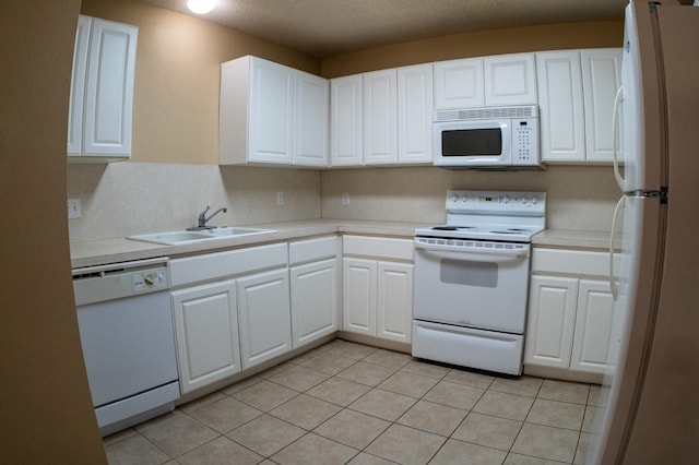 kitchen featuring light tile patterned flooring, sink, white cabinets, and white appliances