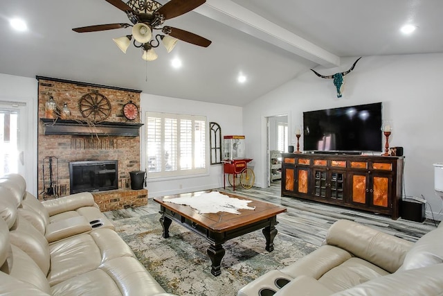 living room featuring lofted ceiling with beams, ceiling fan, a brick fireplace, and light wood-type flooring