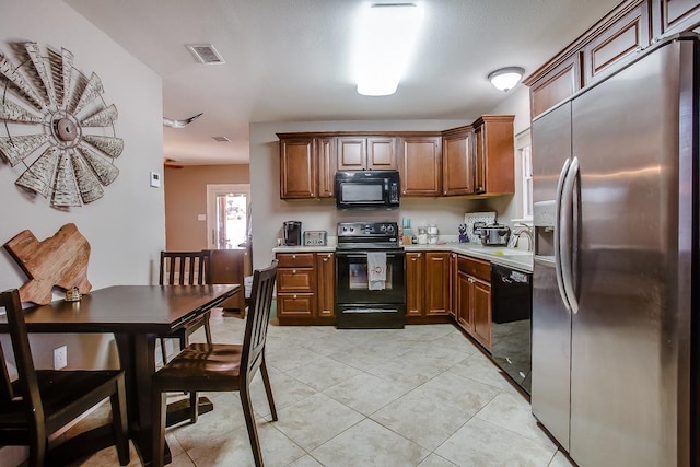 kitchen featuring sink, light tile patterned floors, and black appliances