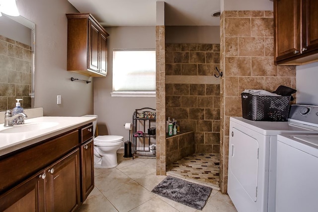 bathroom with a tile shower, vanity, independent washer and dryer, toilet, and tile patterned floors