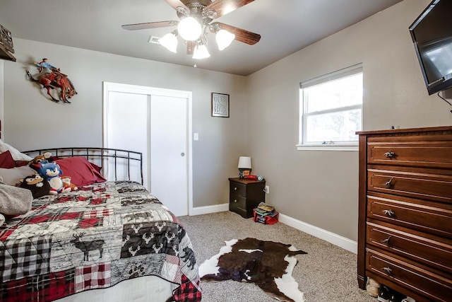 bedroom with light colored carpet, ceiling fan, and a closet