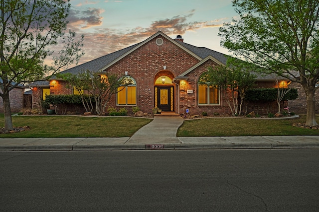 ranch-style house featuring a lawn, a chimney, and brick siding