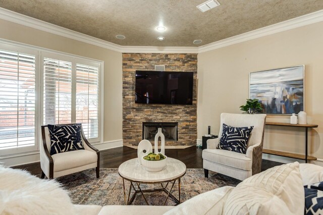 living room with dark wood-type flooring, a fireplace, ornamental molding, and a textured ceiling