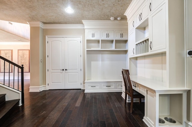 mudroom with crown molding, built in desk, and dark hardwood / wood-style floors