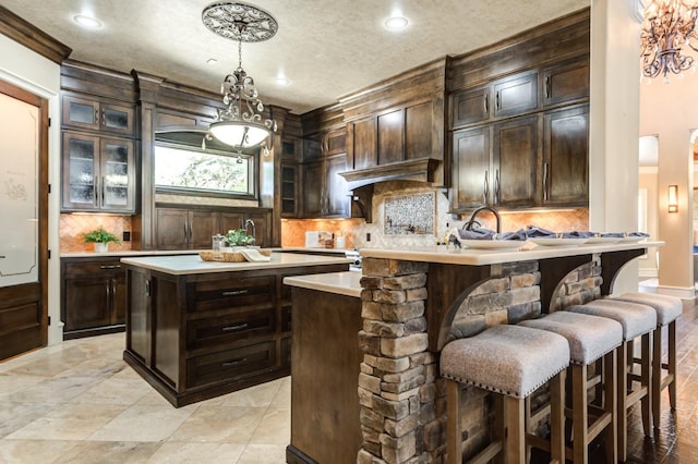 bar featuring hanging light fixtures, dark brown cabinets, and decorative backsplash