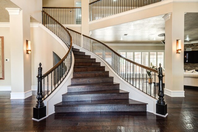 stairs with crown molding, wood-type flooring, and a high ceiling