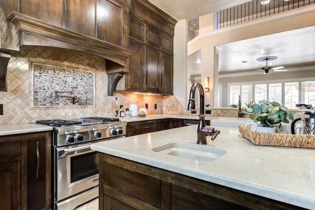 kitchen with tasteful backsplash, sink, dark brown cabinets, and stainless steel range with gas stovetop