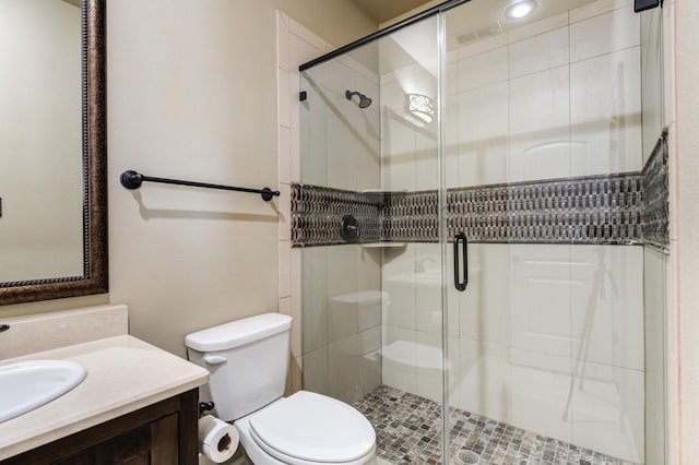 bathroom featuring vanity, a shower with door, and toilet