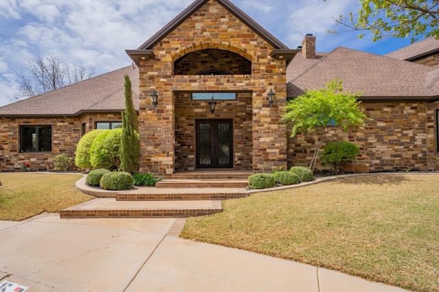 view of exterior entry with a yard and french doors