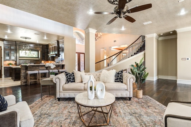 living room featuring dark wood-type flooring, ceiling fan, ornamental molding, vaulted ceiling, and ornate columns