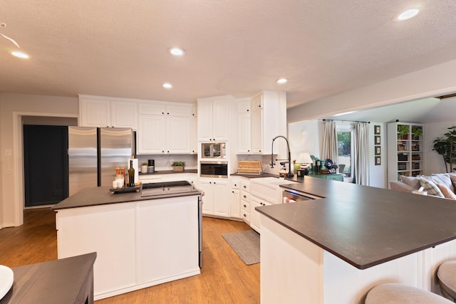 6109 Elkhart Ave, Lubbock, TX 79424 - kitchen featuring freestanding refrigerator, dark countertops, a peninsula, white cabinetry, and light wood-type flooring