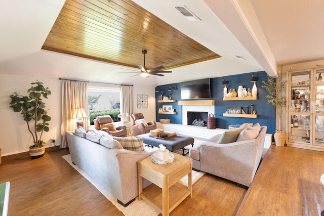 6109 Elkhart Ave, Lubbock, TX 79424 - living room featuring light wood finished floors, ceiling fan, a tray ceiling, a brick fireplace, and wood ceiling