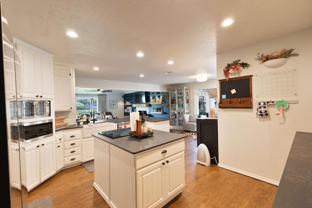 6109 Elkhart Ave, Lubbock, TX 79424 - kitchen with dark countertops, recessed lighting, a kitchen island, light wood-type flooring, and open floor plan