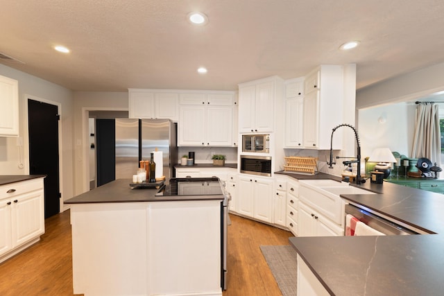 6109 Elkhart Ave, Lubbock, TX 79424 - kitchen with appliances with stainless steel finishes, dark countertops, white cabinetry, light wood finished floors, and a center island