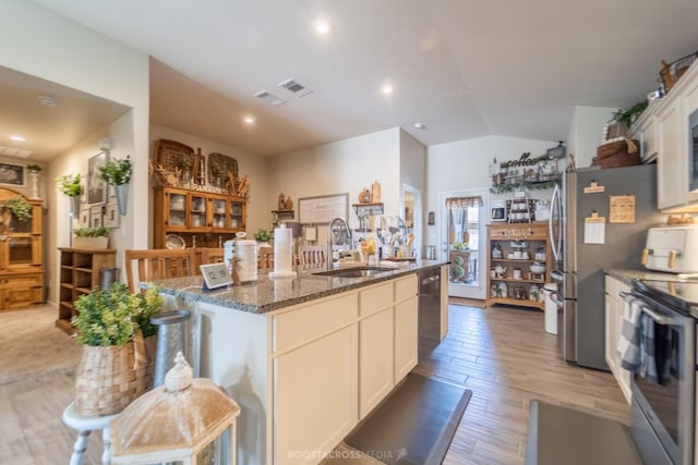 kitchen with sink, a breakfast bar area, white cabinetry, appliances with stainless steel finishes, and a kitchen island with sink