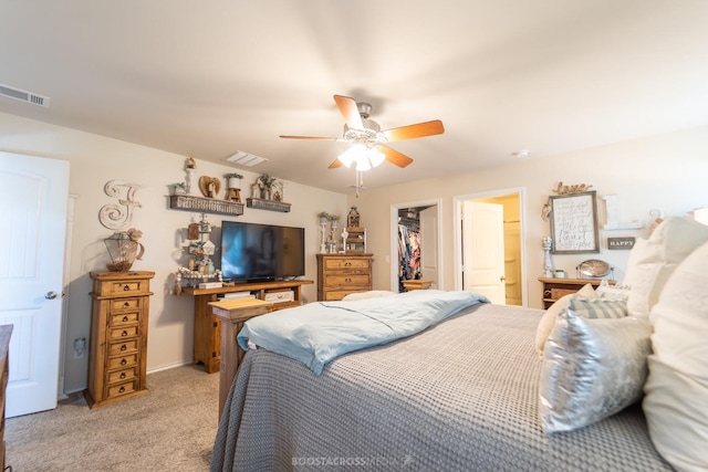 bedroom with a spacious closet, light carpet, ceiling fan, and a closet