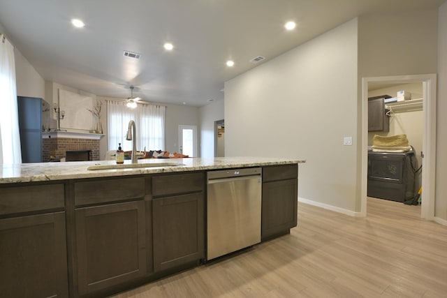 kitchen with washer / clothes dryer, sink, stainless steel dishwasher, light stone countertops, and dark brown cabinets