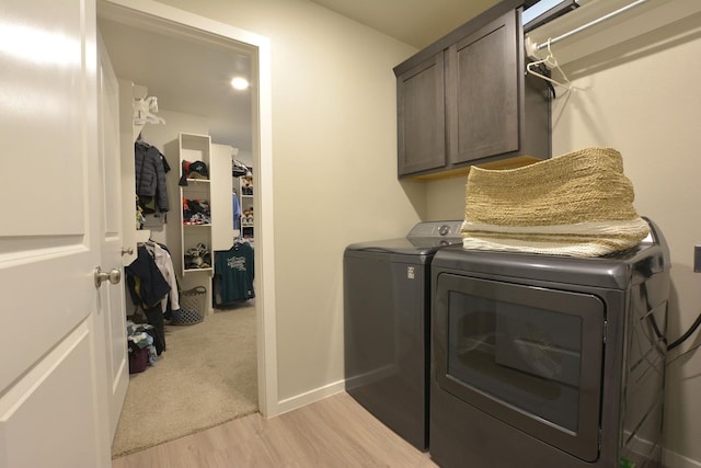 laundry room featuring washer and dryer, light hardwood / wood-style flooring, and cabinets