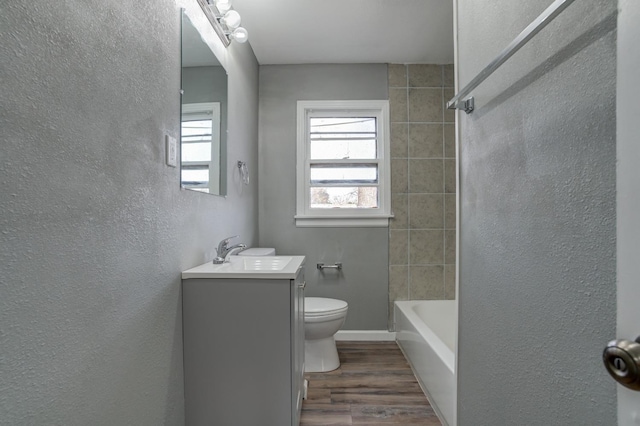 full bathroom with vanity, hardwood / wood-style floors, tiled shower / bath combo, and toilet