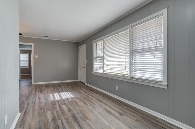 empty room featuring hardwood / wood-style floors, crown molding, and a healthy amount of sunlight