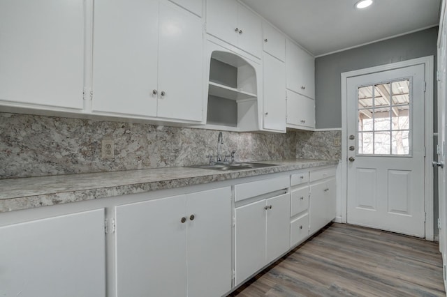 kitchen featuring white cabinetry, sink, decorative backsplash, and light wood-type flooring