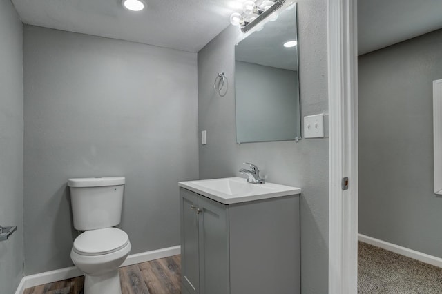 bathroom with vanity, toilet, and hardwood / wood-style floors