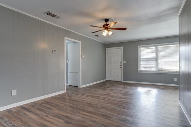 empty room featuring crown molding, dark wood-type flooring, and ceiling fan