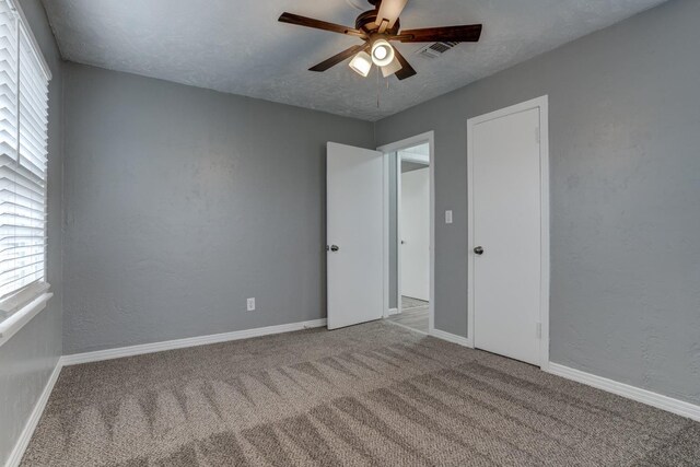 carpeted empty room featuring ceiling fan and a textured ceiling