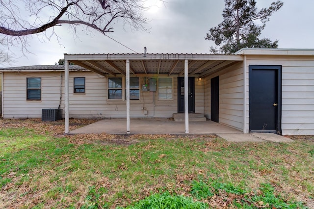 rear view of house with cooling unit, a patio area, and a lawn