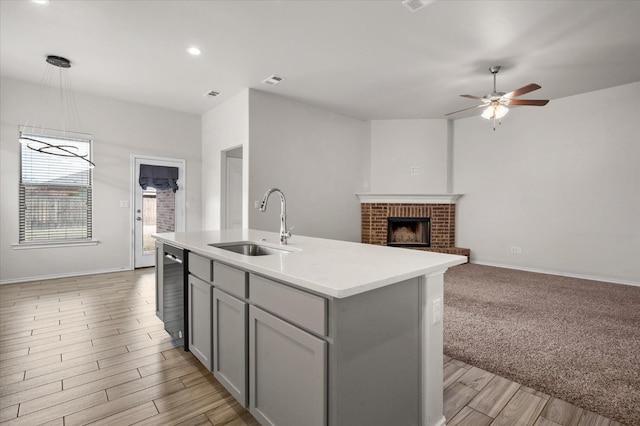 kitchen with pendant lighting, sink, gray cabinetry, wine cooler, and a center island with sink