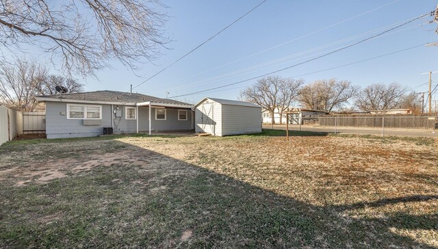 rear view of house with cooling unit, a storage shed, and a yard