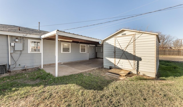 rear view of property with cooling unit, a patio area, and a lawn