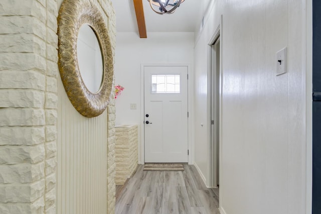 doorway to outside with beam ceiling and light hardwood / wood-style flooring