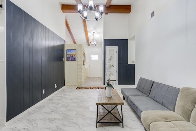 living room featuring beam ceiling, a high ceiling, and an inviting chandelier