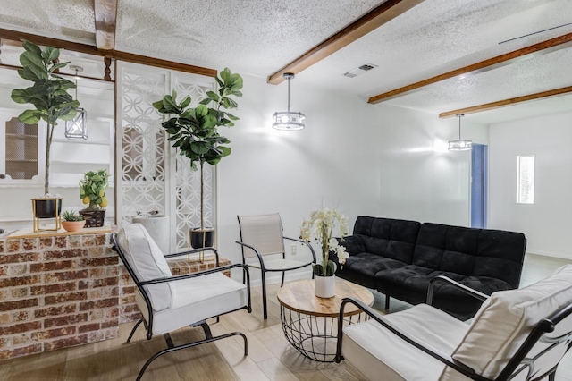 living room featuring beamed ceiling, a textured ceiling, and light wood-type flooring